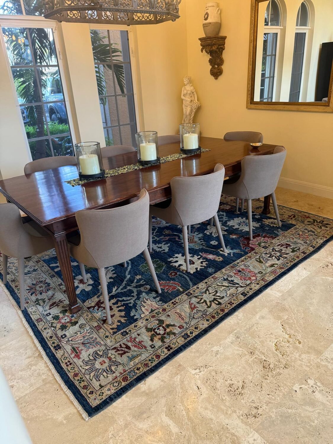 A navy floral rug under a long mahogany dining table with upholstered chairs.